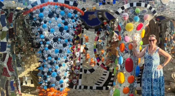 Donna sorride nel Giardino dei Tarocchi, un luogo magico pieno di mosaici colorati e sculture bizzarre.