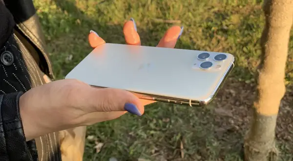 Dłoń trzyma biały iPhone 11. Wymiary telefonu idealnie pasują do dłoni, co widać na zdjęciu.