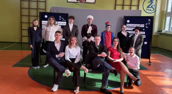 Uczniowie w strojach teatralnych, przygotowujący piosenkę absolwenta.