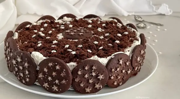 Torta Pan di Stelle decorata con biscotti al cacao e stelline bianche, un dolce che fa sognare.