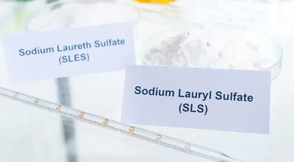 Białe proszki w naczyniach laboratoryjnych, jeden z etykietą "Sodium Laureth Sulfate (SLES)", drugi "Sodium Lauryl Sulfate (SLS)". To właśnie sls co to za substancja?