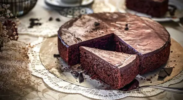 Ein saftiger schokokuchen mit glänzender Glasur, ein Stück wurde bereits herausgeschnitten.