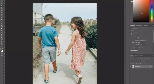 Two children, a boy and a girl, are walking away from the camera. The image is being edited in Photoshop, with a selection tool active, indicating a cut out process.