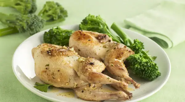 Dos codornices al ajillo doradas y jugosas, servidas con brócoli tierno y perejil fresco. Un plato delicioso y lleno de sabor.