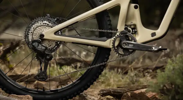 Tylna przerzutka i kaseta napędu rowerowego Shimano Deore LX na piaskowym fullu, gotowe na terenowe wyzwania.