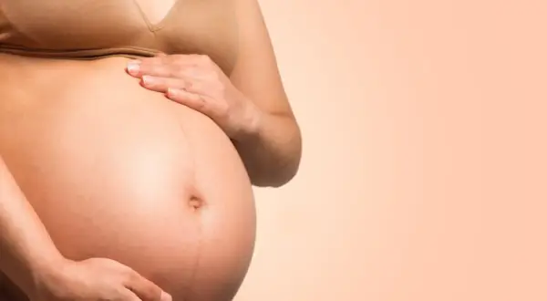 Brzuch ciężarnej kobiety, która zastanawia się, ile wytrzyma dziecko bez wód płodowych.