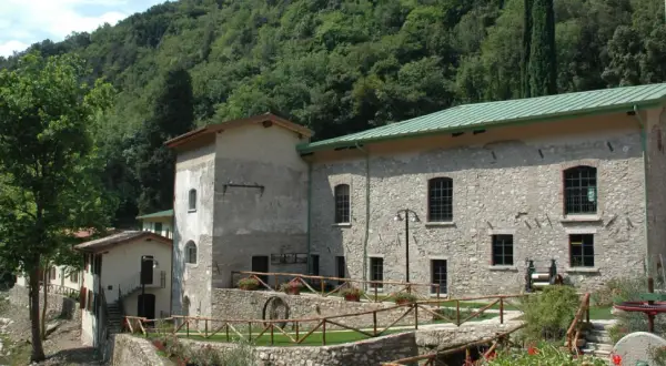 Antica cartiera toscolano immersa nel verde, con un ruscello che scorre e un antico mulino a vista.