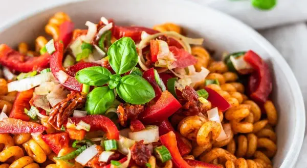 Kolorowa, najlepsza sałatka z makaronem fusilli z papryką, pomidorami suszonymi, cebulą i bazylią.