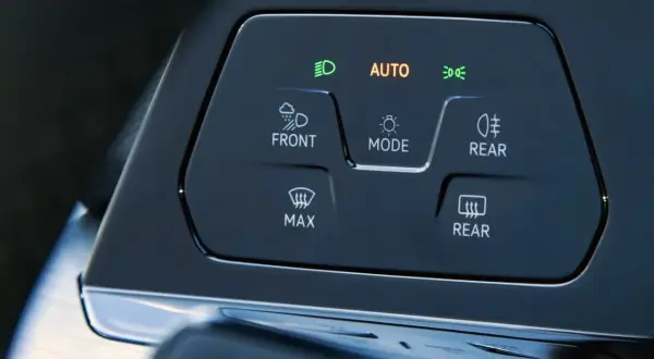 Panel sterowania samochodu z przyciskami: AUTO, FRONT, REAR, MAX. Dowiedz się, jak włączyć światła przeciwmgielne.