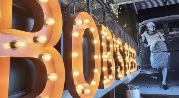 Lettre enseigne lumineuse "BOBSTER" sur fond d'une fresque vintage.