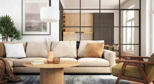 Gemütliche zimmer einrichtung mit beigem Sofa, Holztisch und grüner Sessel. Im Hintergrund offene Küche mit Holzelementen.