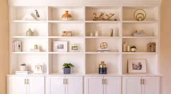 A beautifully styled built-in shelving unit showcases decorative objects, books, and framed photos.