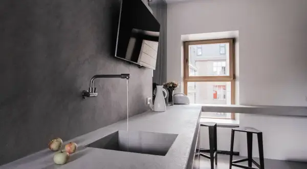 Encimera de cocina moderna con fregadero integrado de microcemento. Grifo cromado y tres manzanas sobre la superficie.