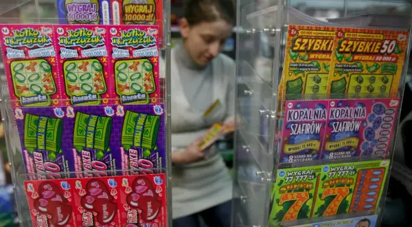 Zdrapki "Pieniądze jak lodu" i inne losy na loterii w kiosku. Kobieta wybiera zdrapkę.