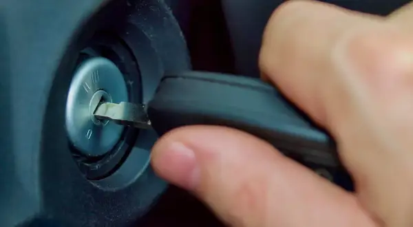 Main d'une personne insérant une clé dans le Neiman d'une voiture. Le prix du changement de Neiman est une préoccupation courante.