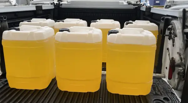 Kilka żółtych kanistrów z płynem, prawdopodobnie olej opałowy, w bagażniku samochodu. Sprawdzamy aktualną olej opałowy cenę.