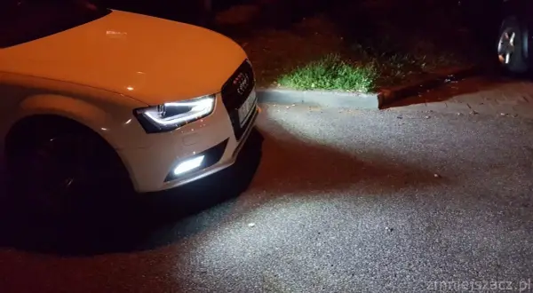 Białe Audi A4 B8 po lifcie z zapalonymi światłami przeciwmgielnymi. Wymiana żarówki przeciwmgielnej zakończona sukcesem.