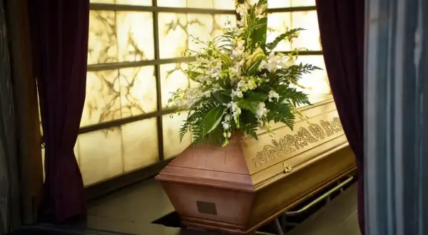 Drewniana trumna z kwiatami, przygotowana do pochówku. Śmierć Polaka za granicą to trudne procedury, ale godne pożegnanie jest ważne.