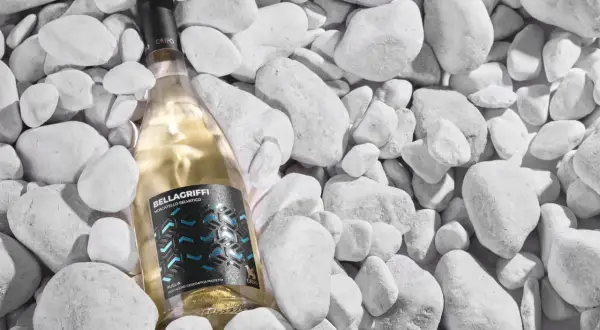 Un vino pugliese bianco, Bellagriffi Moscatiello Selvatico, riposa tra ciottoli bianchi.