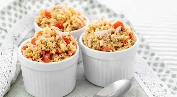 Tre coppette bianche piene di cous cous tonno e pomodorini, un piatto fresco e colorato.