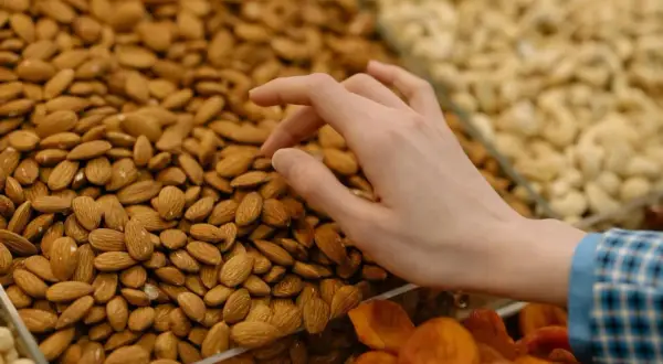 Mano seleccionando almendras para aprender como hacer harina de almendras. Se ven secas y listas para moler.