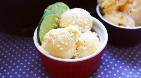 Krämig kvarg glass med kokosflingor och lime i en röd skål. En perfekt sommardessert!