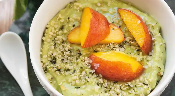 Grön smoothiebowl med avokado, toppad med persikoklyftor och hampafrön. Ett enkelt och gott avokado recept.