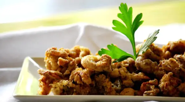 Camagroc crujiente en un plato blanco, decorado con perejil fresco. ¡Un bocado delicioso!