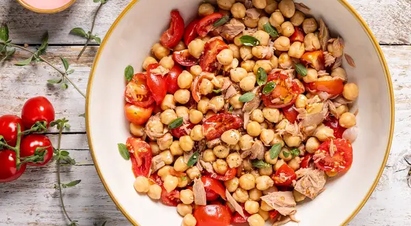 Un'insalata di ceci estiva con pomodorini freschi e tonno, guarnita con erbe aromatiche. Perfetta per un pasto leggero e gustoso.