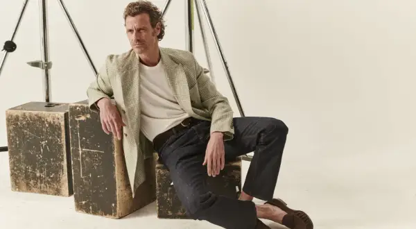 Uomo con un blazer a quadri e jeans scuri, un look fit slim perfetto per ogni occasione.