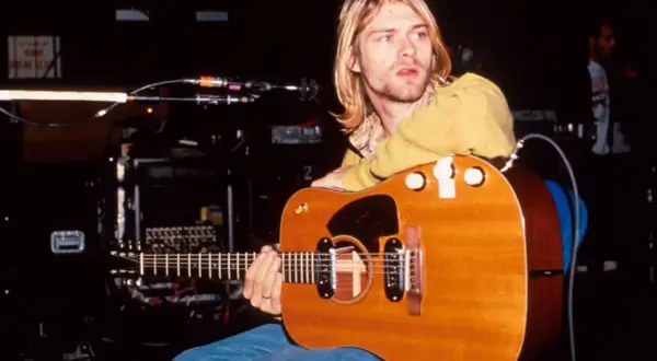 Kurt Cobain z gitarą akustyczną, symbol grunge'u i muzyki, która zdefiniowała pokolenie.