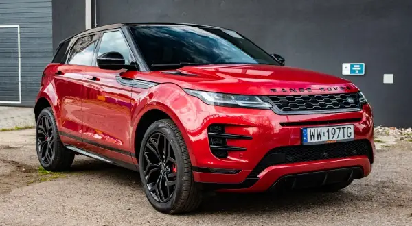 Czerwony Range Rover Evoque z czarnym dachem i felgami. Wiele osób szuka o nim pozytywnych **range rover evoque opinie**.