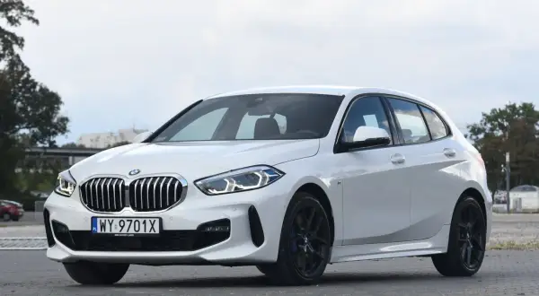 Białe BMW 118d z czarnymi felgami stoi na parkingu.