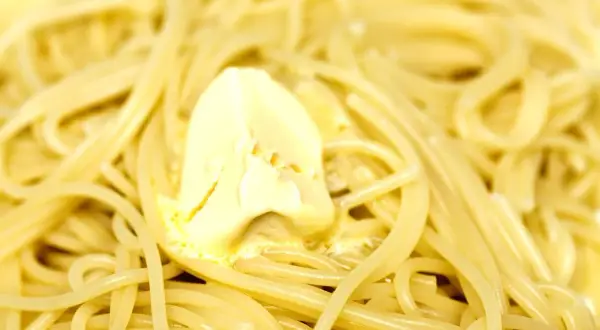 Spaghetti fumanti con una generosa porzione di burro che si scioglie, un classico piatto di pasta in bianco.