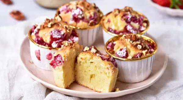 Puszyste muffinki z truskawkami, posypane orzechami, kuszą swoim wyglądem i zapachem. Idealne na deser.
