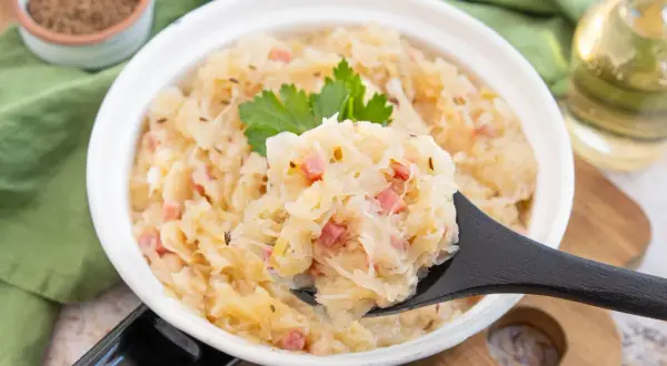 Sauerkraut kochen nach Omas Rezept: herzhaftes Gericht mit Speck und Kümmel, garniert mit Petersilie.
