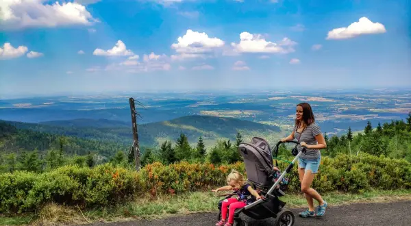 Mama z córką na spacerze, gdzie w góry z wózkiem. Piękny widok na dolinę i chmury.