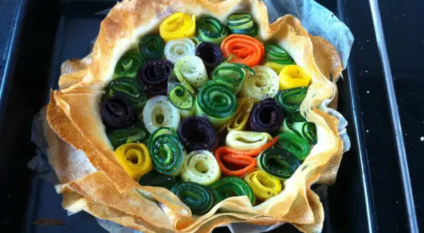 Une quiche aux légumes colorés, enroulés en spirales, dans une pâte croustillante.