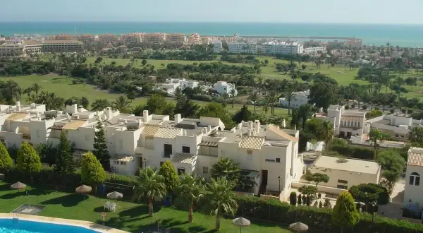 Vista aérea de Almerimar: complejos residenciales blancos, campo de golf verde y el mar azul. Ideal para saber qué ver en Almerimar.