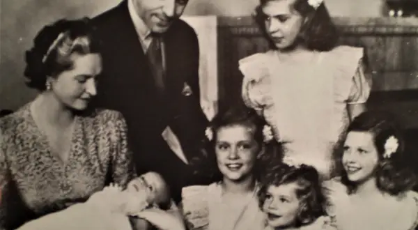Familjefoto med prinsessan Sibylla och hennes barn. Bilden visar en familj med föräldrar och flera barn, inklusive en bebis. Prinsessan Sibylla bar en mönstrad klänning.