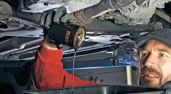 Mechanik wymienia stary olej silnikowy. Pamiętaj, co ile się wymienia olej, by auto służyło latami.