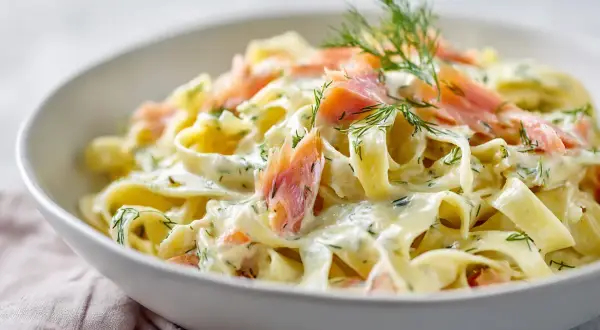En skål med krämig pasta med laxsås, toppad med dill och laxbitar. En riktig svensk klassiker!