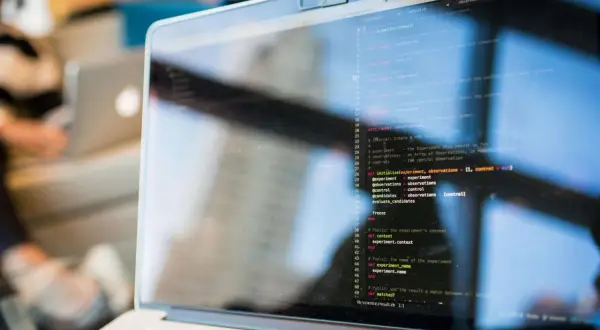 Programista kod zawodu, pisze kod na laptopie. Widać fragment ekranu z kodem w języku Ruby.