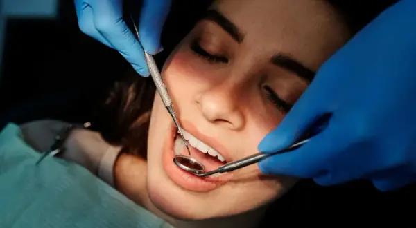 Dentysta bada zęby pacjentki, szukając oznak problemów, takich jak halitoza objawy.