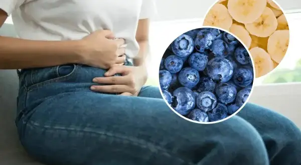 Osoba z bólem brzucha trzyma się za żołądek. Obok zdjęcia jagód i plasterków banana, które mogą pomóc na biegunkę.
