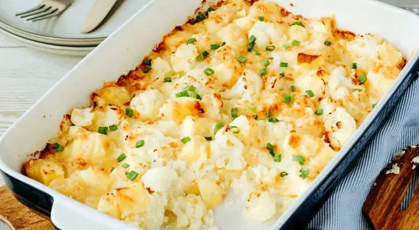 Ein goldbrauner Blumenkohlauflauf mit Käse überbacken und mit Schnittlauch bestreut, bereit zum Servieren.