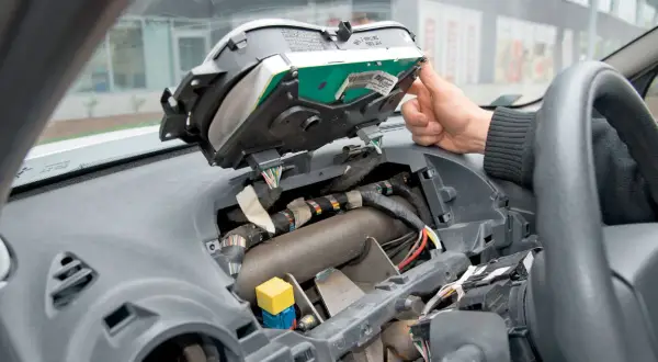 Wymiana żarówek przód w Opel Vivaro. Widok wnętrza zdemontowanego kokpitu, widoczne przewody i elementy deski rozdzielczej.
