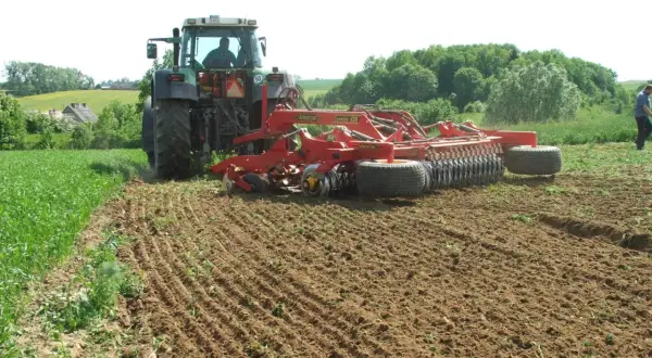 Traktor z agregatem uprawowym wykonuje podorywkę na polu.
