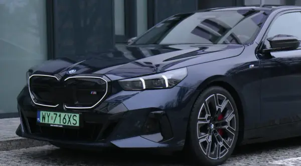 Eleganckie bmw serii 5 w ciemnym kolorze, z charakterystycznym grillem i sportowymi felgami, zaparkowane na brukowanej nawierzchni.