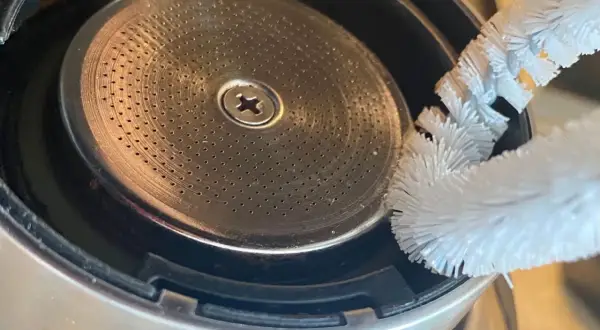 Szczoteczka czyści młynek do kawy w ekspresie DeLonghi. Drobne otwory sitka wymagają regularnego czyszczenia, by kawa była zawsze świeża.